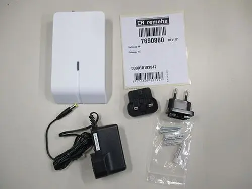 Weißes Gerät von Remeha, dazu ein Netzadapter, mehrere Steckdosenadapter und eine Tüte mit Schrauben und Dübel zur Befestigung.